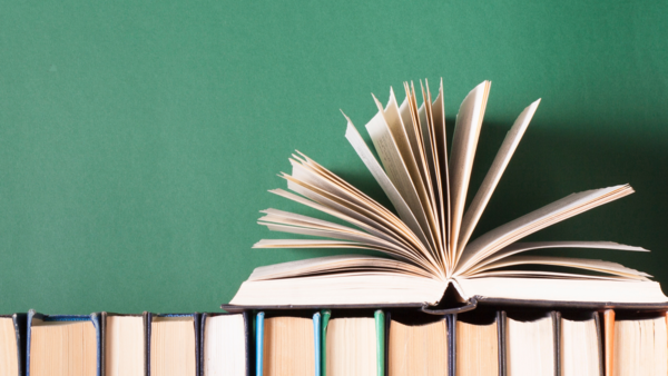 An open book with pages flared on top of many books